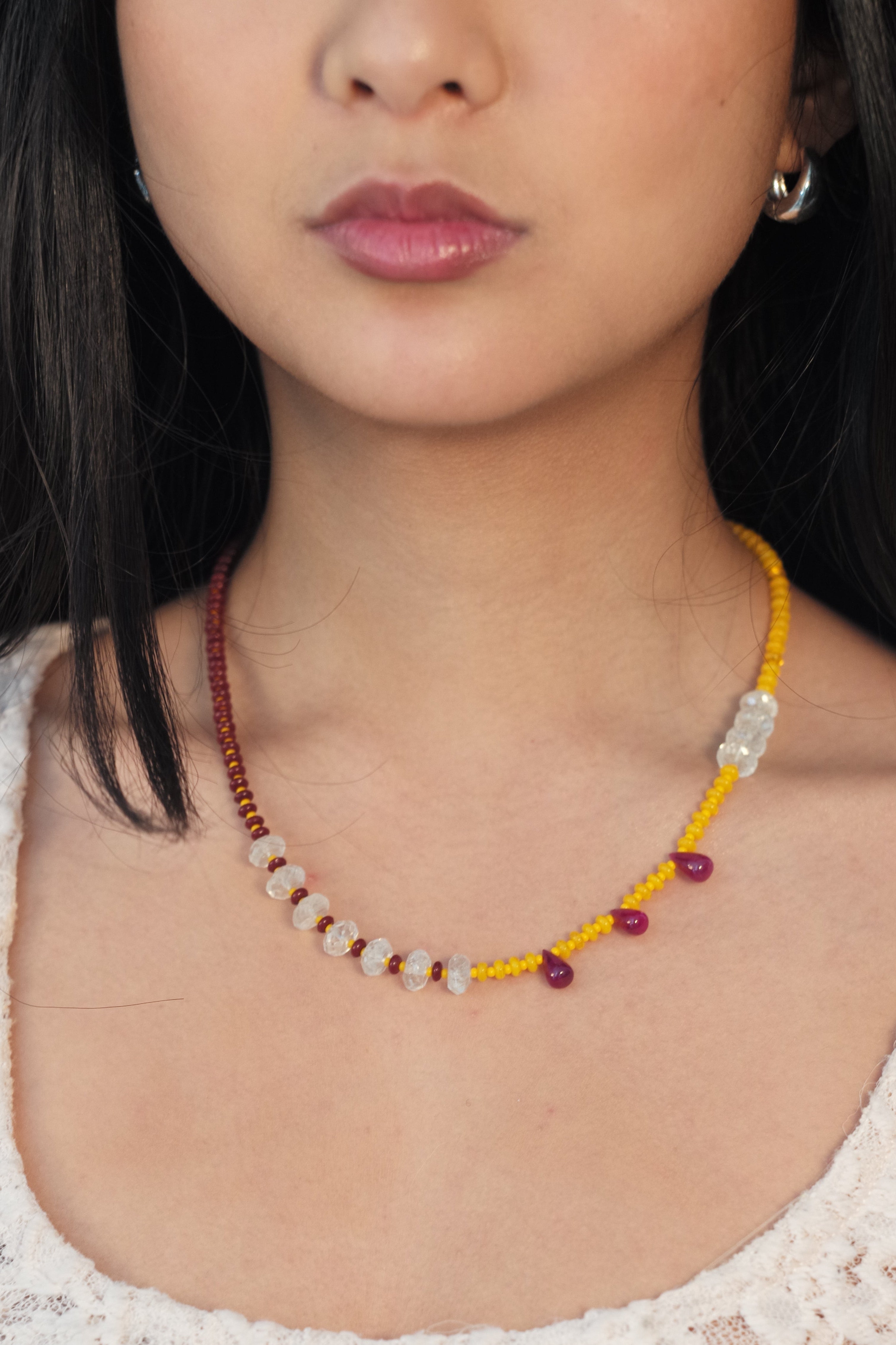 Close-up of a person wearing a beaded necklace with a soft background