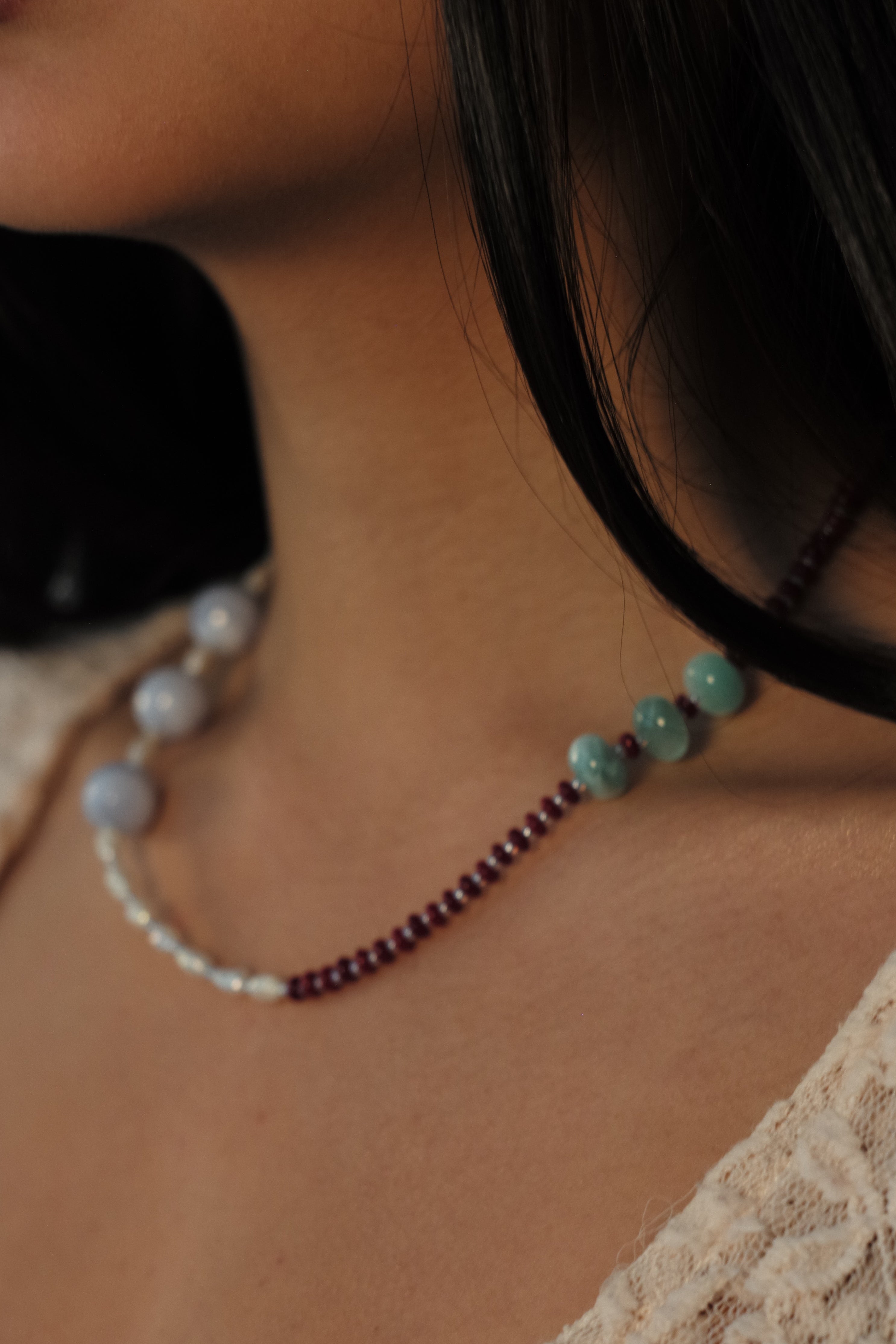Close-up of a person wearing a beaded necklace with a lace garment.