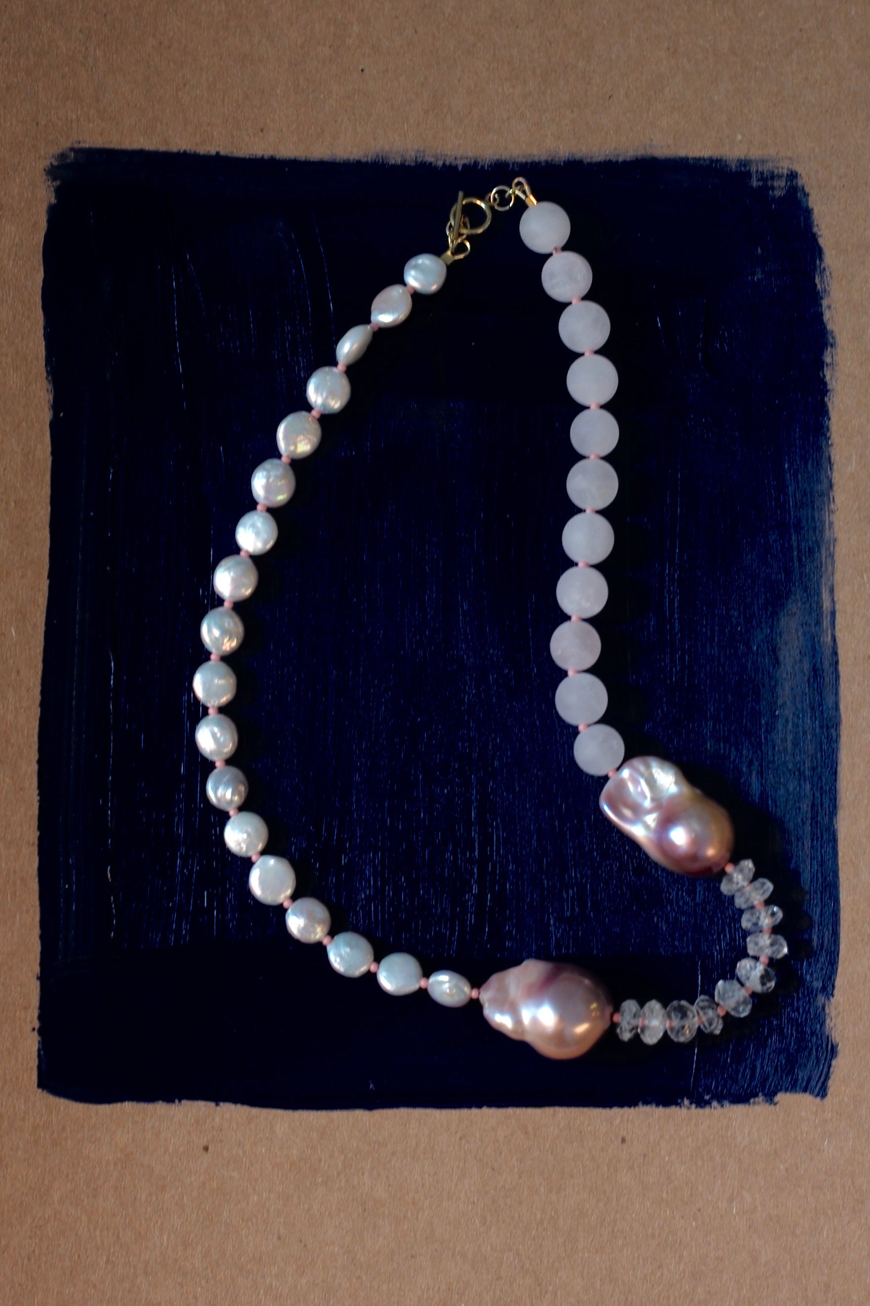 Pearl necklace with a clasp on a dark blue fabric background